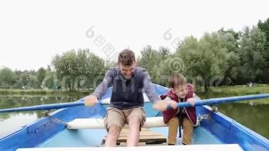 快乐的父子在公园的湖上享受乘船旅行。 快乐的家庭一起在户外度过时光。 父亲和孩子玩游戏